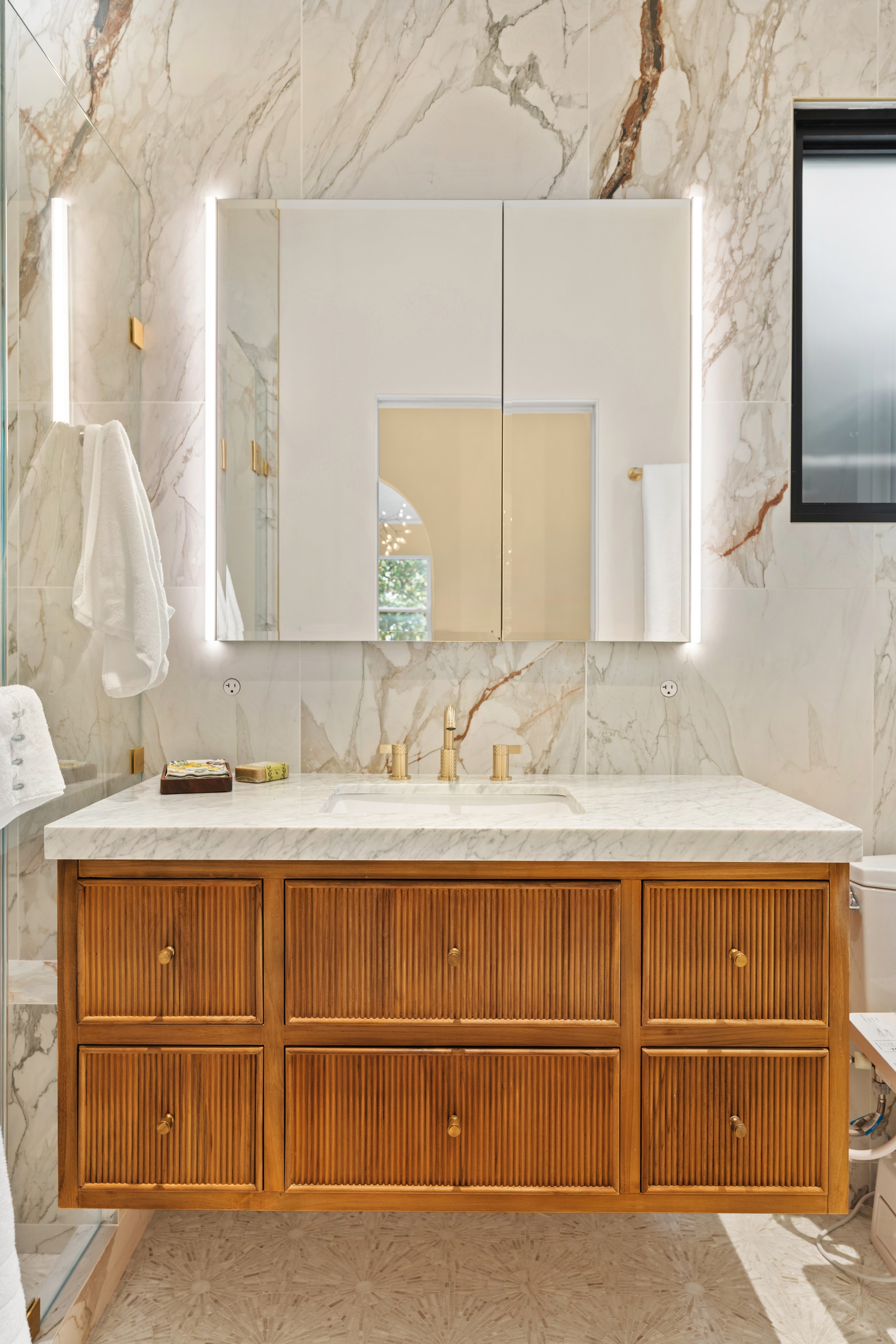 Marble shower with brass fixtures and built-in niche